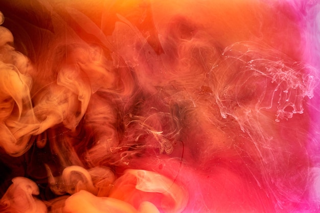 Оранжево-розовый дым на фоне черных чернил красочный туман абстрактный кружащийся сенсорный океан море акриловая краска пигмент под водой