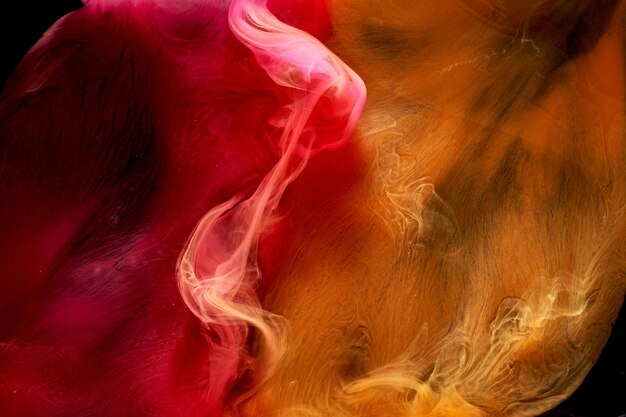 Orange pink smoke on black ink background colorful fog abstract swirling touch ocean sea acrylic paint pigment underwater