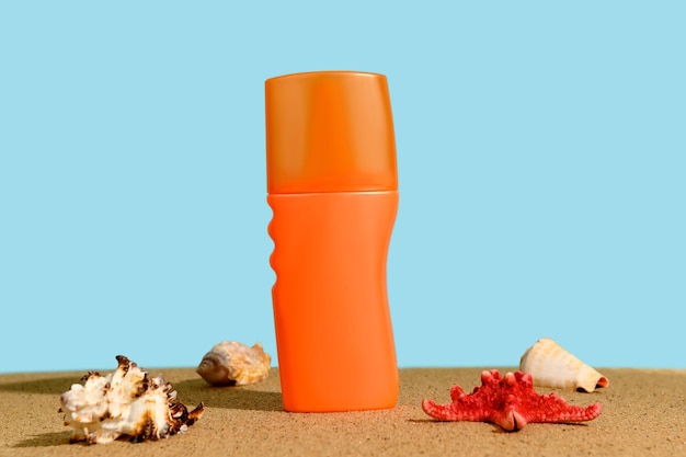 砂の上にあるオレンジ色のプラスチックボトルと海星の化品クリーム