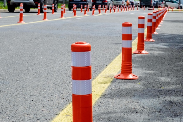 Orange plastic poles on the road to separate lanes stand in a row
