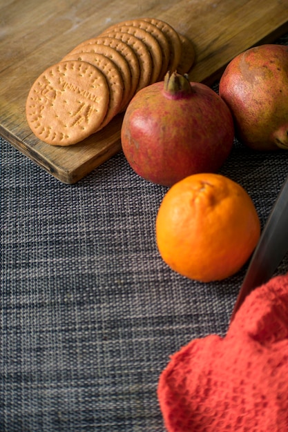 ビスケットとナイフでテーブルマットの上に置かれたオレンジザクロの果実