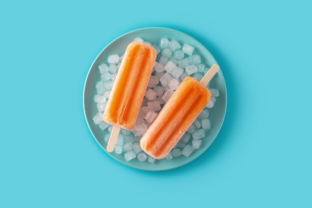 Оранжевое фруктовое мороженое на синей тарелке на синей поверхности