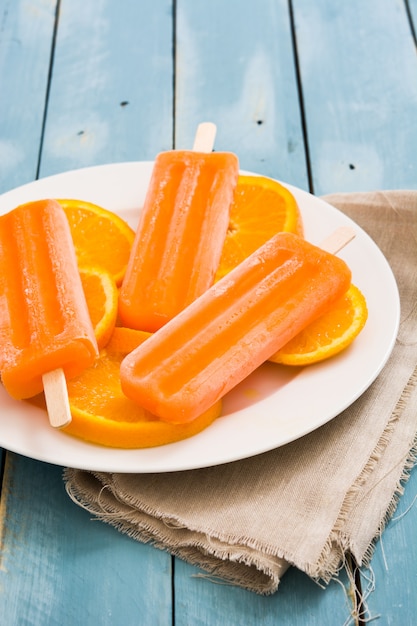 Orange popsicles on blue wooden table