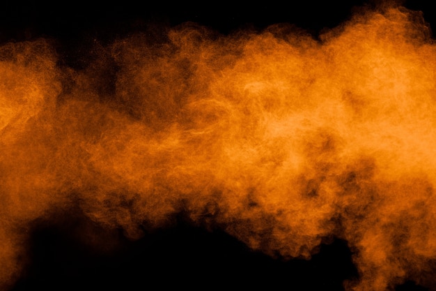 Orange powder explosion on black background. Orange color dust splash.