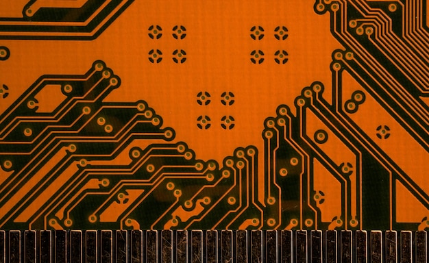 Orange printed circuit board with scratched golden connectors, closeup detail