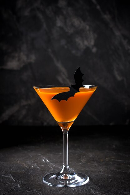 Orange pumpkin  martini Halloween drink for party over black background with copy space