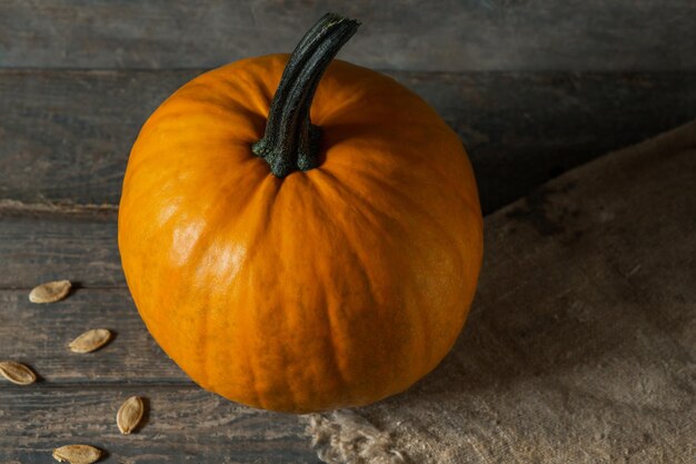 Orange pumpkin on wooden boards for halloween holiday seeds burlap