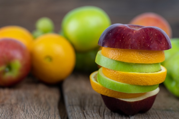오렌지, 빨간 사과, 녹색 사과 나무 바닥에 조각으로 잘라