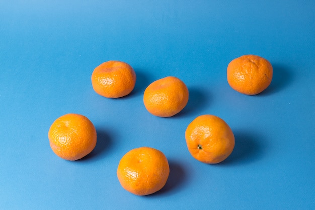 Orange ripe mandarin or tangerine fruit layout over blue colorful background.