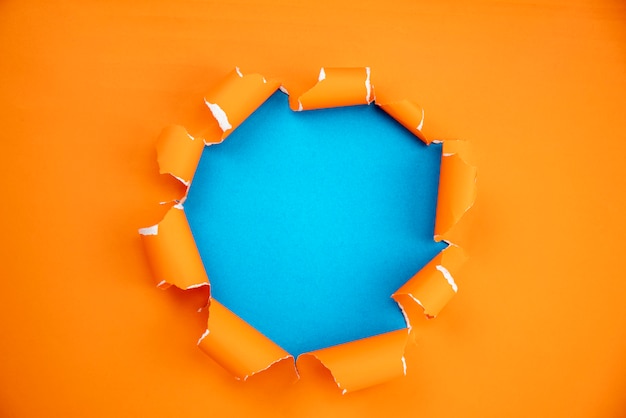 Orange ripped open paper on blue paper background