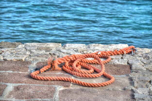 海沿いの岩だらけの桟橋にオレンジ色のロープ