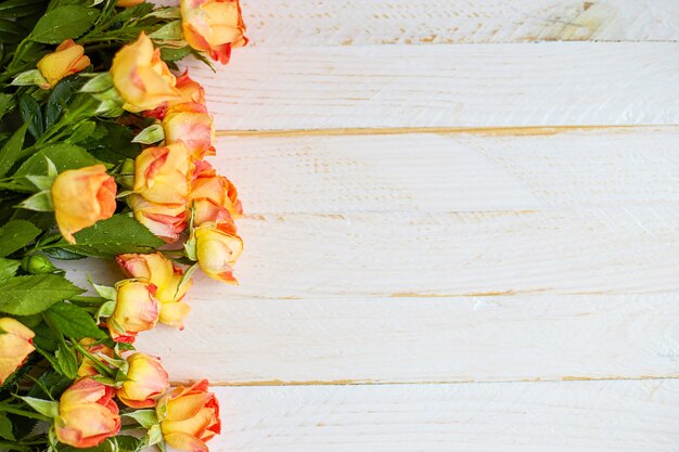 Orange roses on white surface with wooden texture