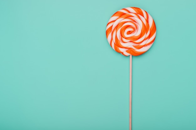 Orange round lollipop on blue surface