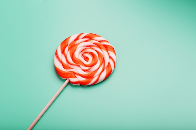 Orange round lollipop on blue surface