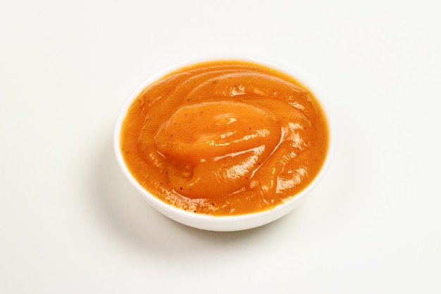 Orange sauce in white plate on white background.