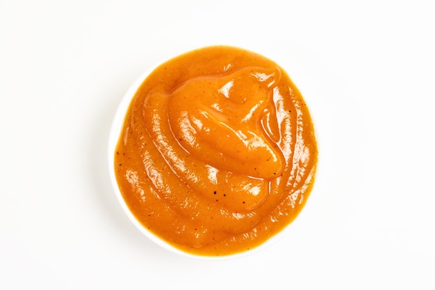 Orange sauce in white plate on white background.