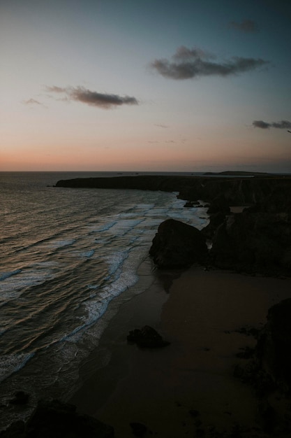 Orange sky over the gloomy rocky beach