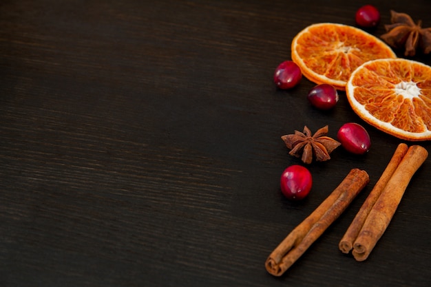 Orange slices, cranberries, cinnamon and anise on a dark.