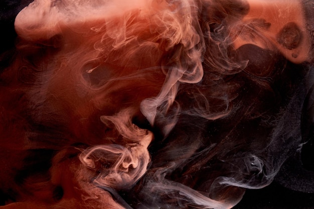 Orange smoke on black ink background colorful fog abstract swirling touch ocean sea acrylic paint pigment underwater