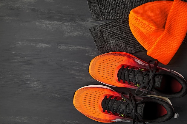 Orange sneakers orange knitted hat warm running leggings on a dark wooden table