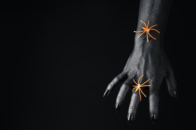 Orange spiders on black female hand on black background space for text