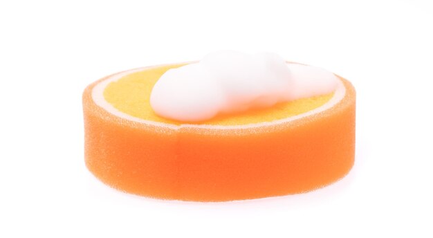 Оранжевая губка мокрая с пеной на белом фоне.