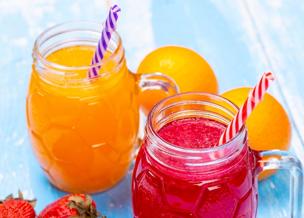 The orange and strawberry juice on blue wooden table