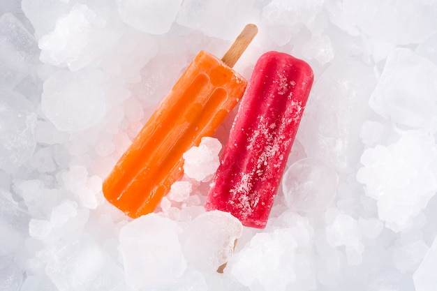 Orange and strawberry popsicles on ice cubes