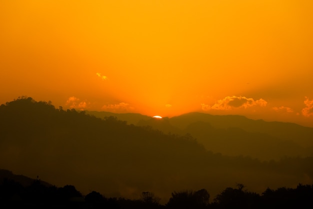 Orange sun fino all'alba sulla montagna e riflettere sul fiume con fumo di nebbia mattutina.