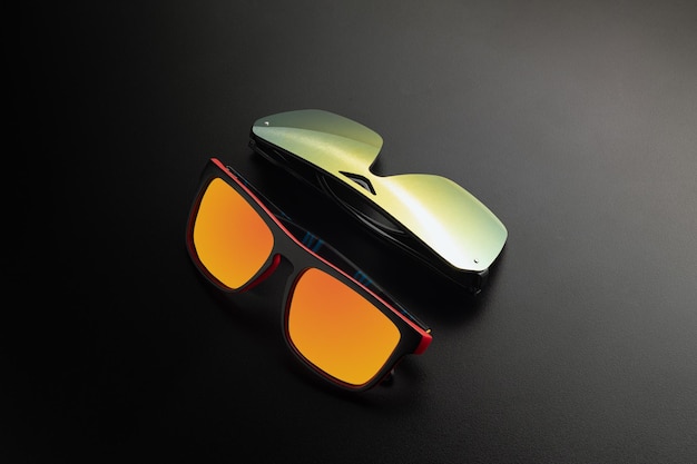 Orange sunglasses with dark background. black rim and orange glass. dramatic shadow effect