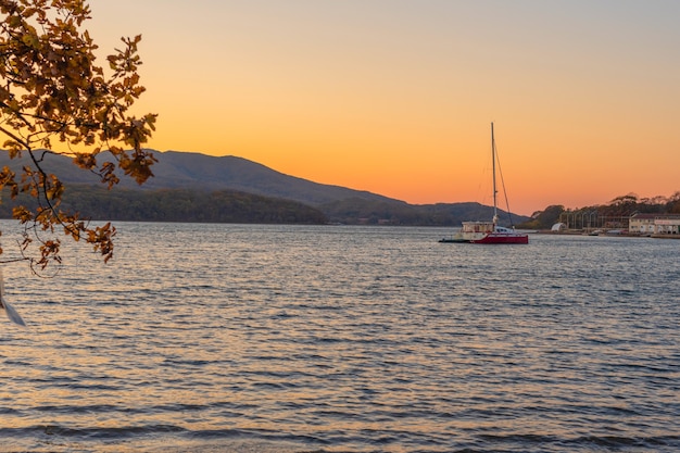 Tramonto arancione in riva al mare con yacht sull'acqua