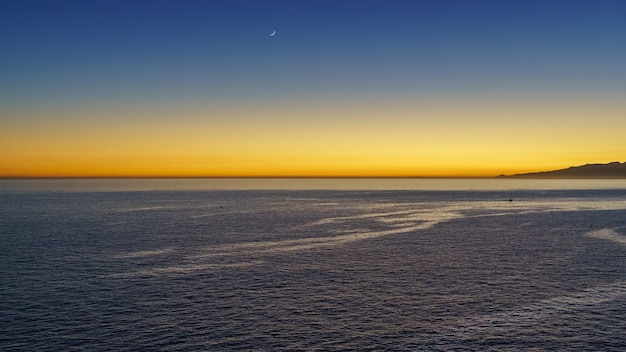 太陽が海の地平線上に消えた後のオレンジ色の夕日の光。スペイン、ヨーロッパ。