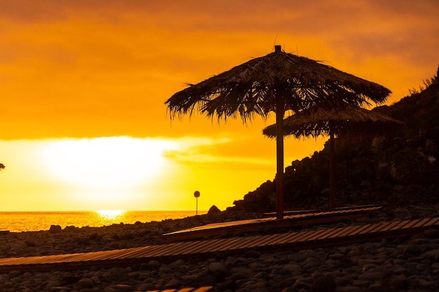 Orange sunset on the umbrellas at Ponta do Sol beach Madeira Portugal