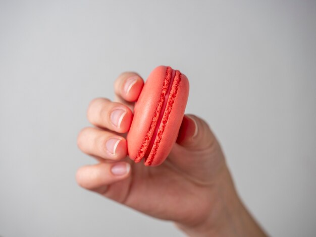 Orange sweet macaroon cookies in hand on a white background. Close-up, air-conditioning product