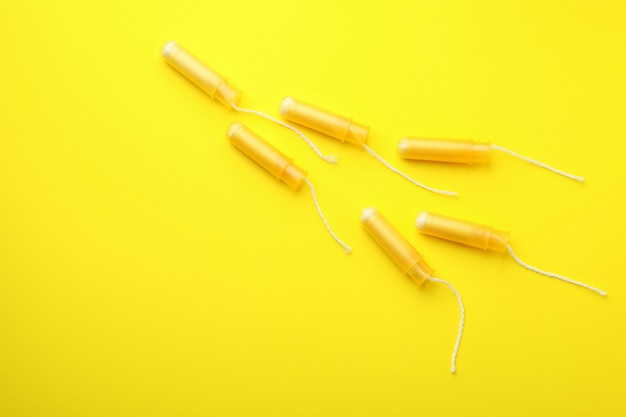 Orange tampons on yellow background