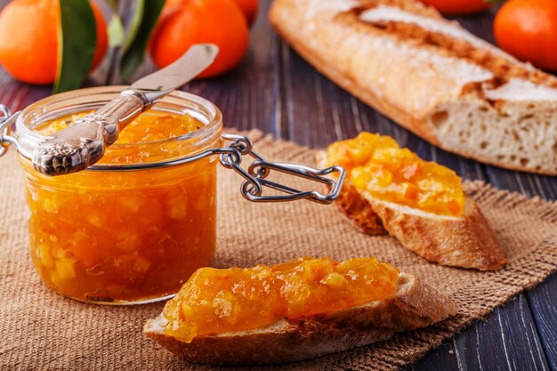 Orange (tangerine) jam in a glass jar on the table.