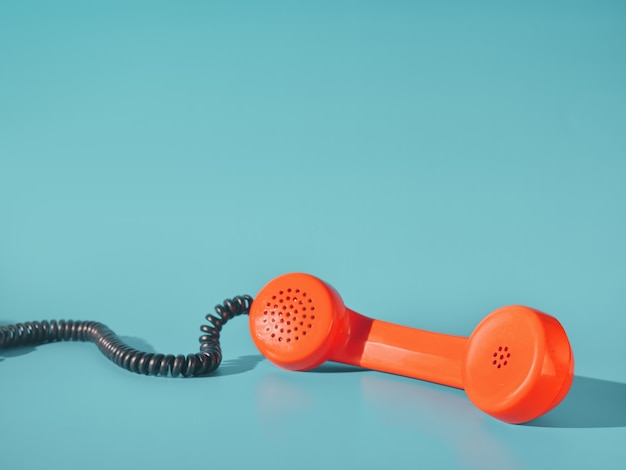 Photo orange telephone receiver on blue background