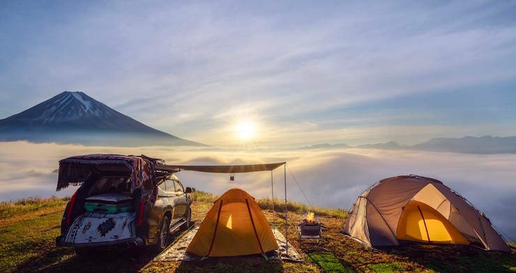Photo オレンジ色のテントと山の頂上でキャンプ 霧の海と山頂の景色と日の出の時間の前に そしてテントと旅するための車があります