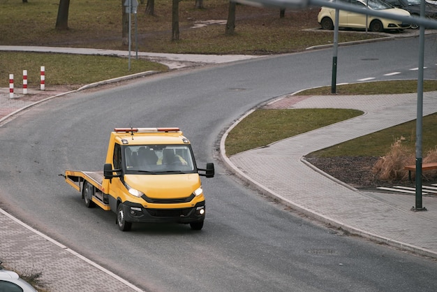 Foto un rimorchiatore arancione con un piano e un verricello nella parte anteriore è pronto ad assistere un'auto rotta in una strada della città