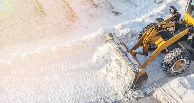 Orange tractor removes snow from the road and clears the sidewalk.Snow removal after snowfalls