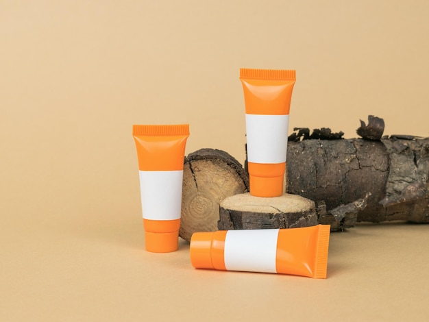 Orange tubes with white letterheads on an old tree on a beige background