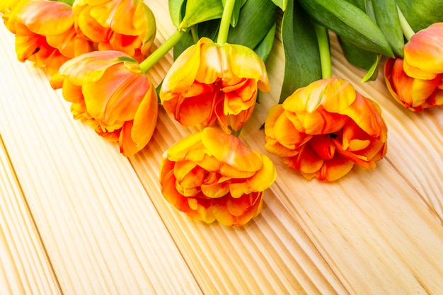 Orange tulip flowers on a wooden table