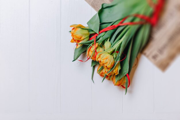 Tulipani arancioni su fondo di legno bianco