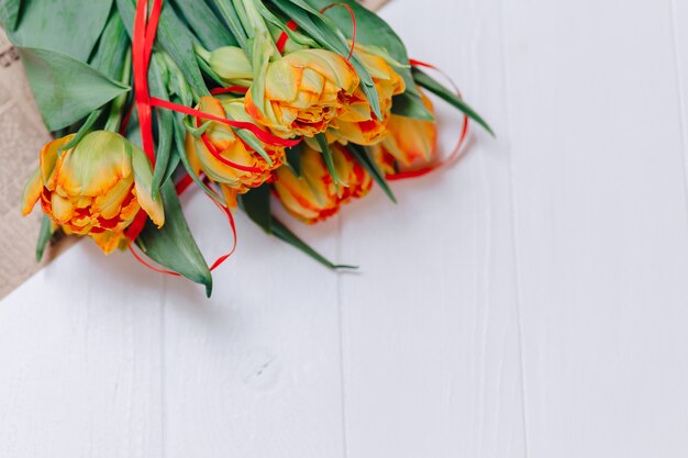 Tulipani arancioni su fondo di legno bianco