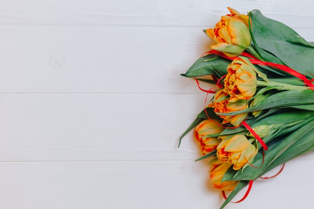 Orange tulips on white wooden background