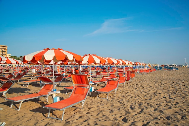 에밀리아로마냐(EmiliaRomagna)의 아드리아 해(Adriatic coast)에 있는 이탈리아 리미니(Rimini) 해변의 주황색 우산과 의자 라운지