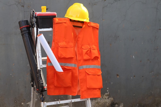 Orange vest and yellow hardhat for work safety protection with construction equipment