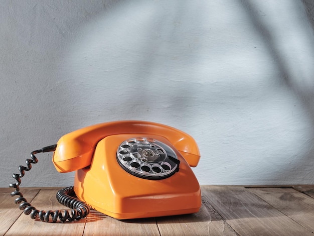 Orange vintage telephone on gray background