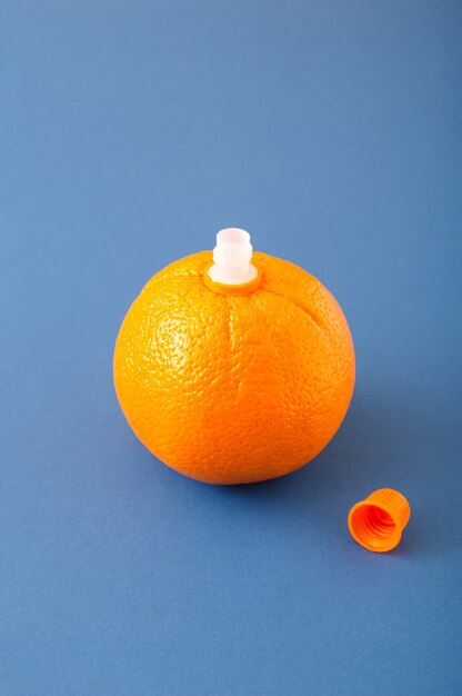 Orange on which there is a juice stopper and a lid on the side on a blue background. Food citrus fruit still life concept.