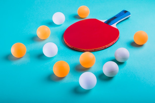 Foto una palline arancione e bianco con la racchetta da ping pong su sfondo blu